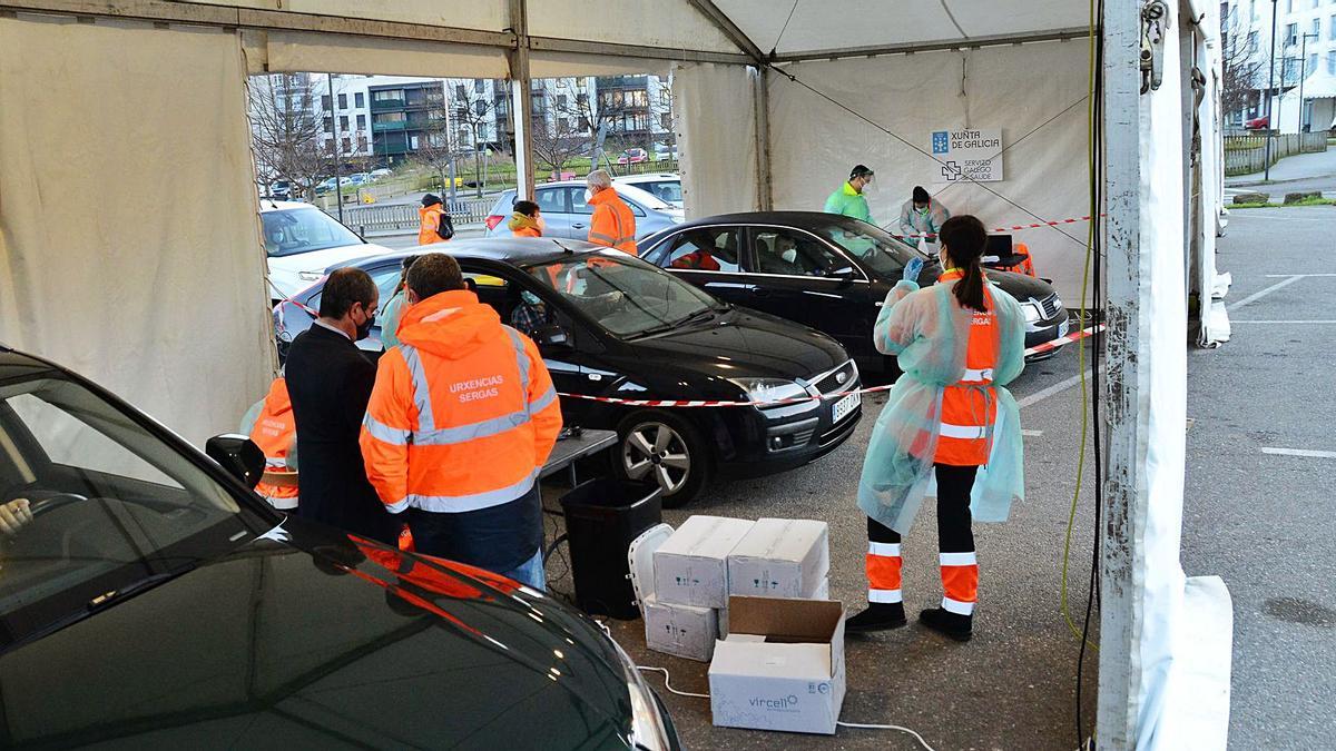 El equipo sanitario entrega, ayer, a los ocupantes de varios coches los tubos para las muestras de saliva en la carpa de As Lagoas.   | // G.NÚÑEZ