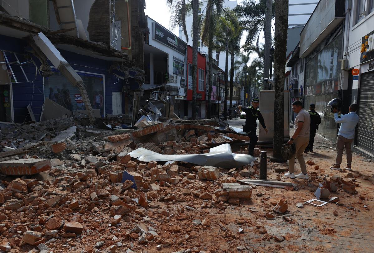 Personas caminan frente a una edificación afectada tras un fuerte temblor en Colombia. Personas caminan frente a una edificación afectada tras un fuerte temblor en Colombia.
