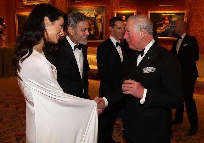 El Príncipe Carlos saluda a Amal Clooney y a su marido, Geroge.