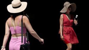 Primera noche tropical del verano. En la foto, dos mujeres se protegen del calor con sendos sombreros, en Valencia.