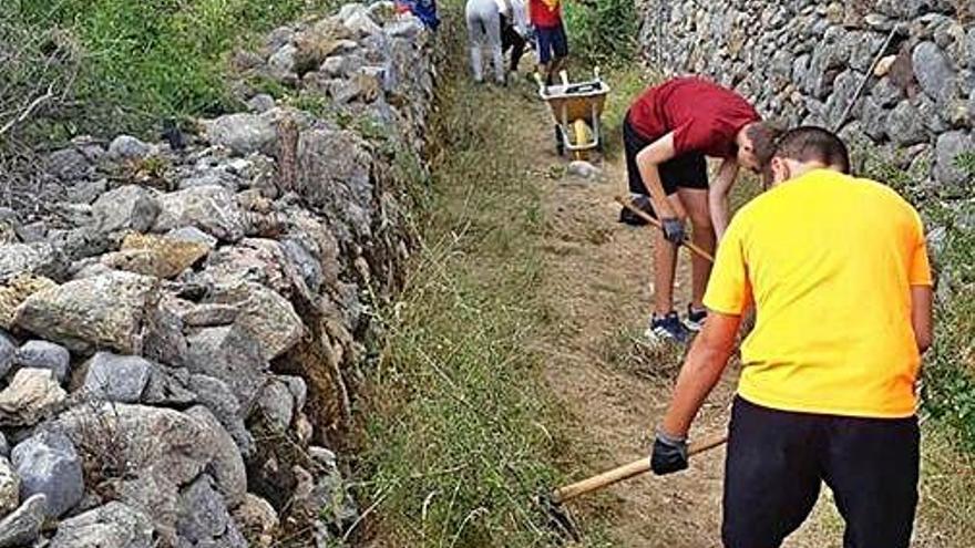 Joves del camp de treball arreglant els murs de pedra seca