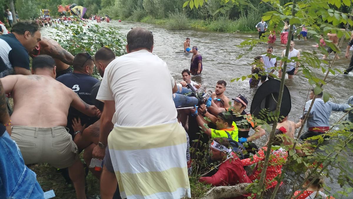 Sanitarios y participantes, ayudando en el traslado de la camilla de una orilla a otra del Nalón.