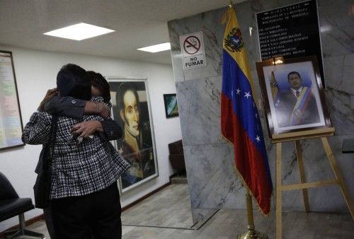 Employees of Venezuela's embassy hug while standing next to a photograph of Chavez in Mexico City