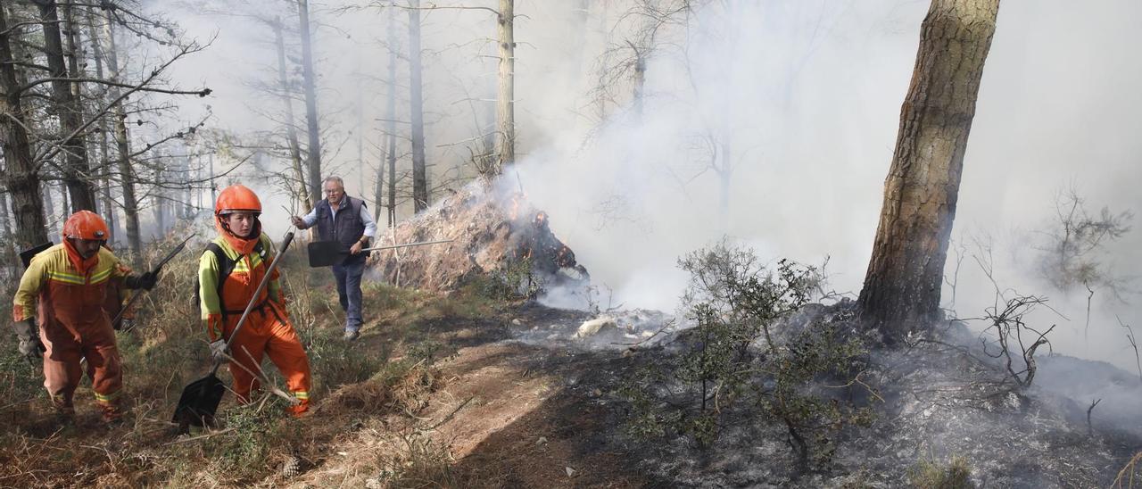 Operarios ayudan a extinguir las llamas en uno de los incendios de Asturias.