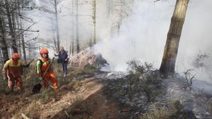 Operarios ayudan a extinguir las llamas en uno de los incendios de Asturias.