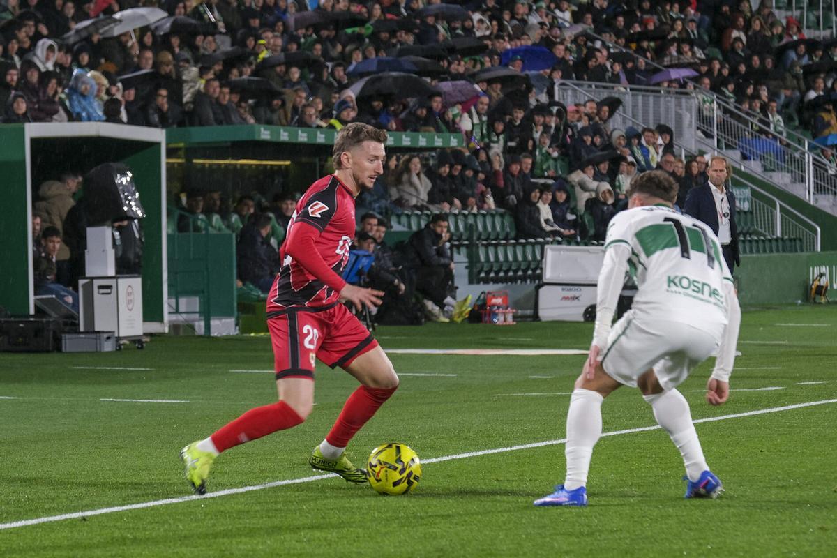 ELCHE (ALICANTE), 21/12/2025.- El defensa albanés del Rayo Vallecano, Ivan Balliu (i), con el balón ante el delantero del Elche, Germán Valera, durante el partido de la jornada 17 de LaLiga EA Sports, que disputan hoy domingo Elche CF y Rayo Vallecano en el Estadio Manuel Martínez Valero. EFE/ Pablo Miranzo