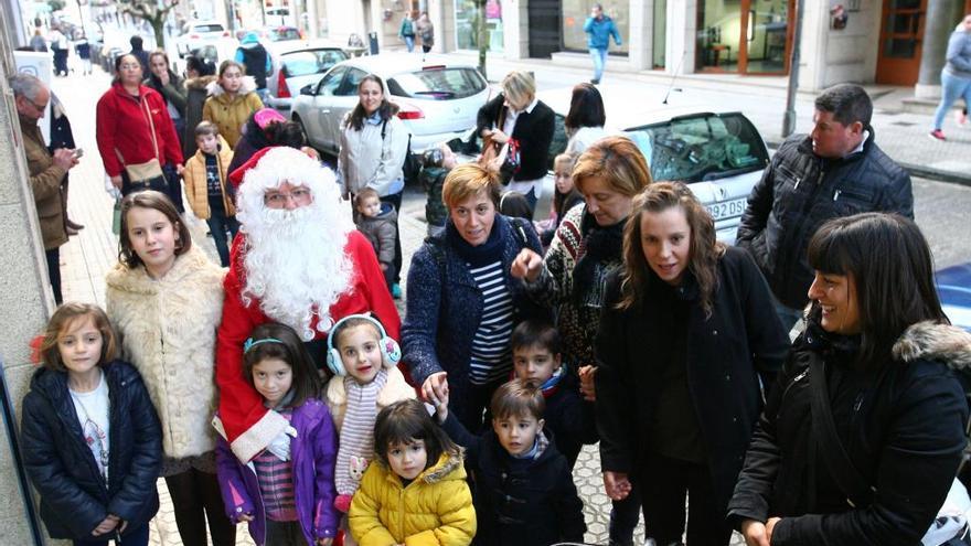 Papá Noel, esta tarde, con niños de A Estrada ante el estudio fotográfico de Bernabé en la villa. // Bernabé / Adrián Rei