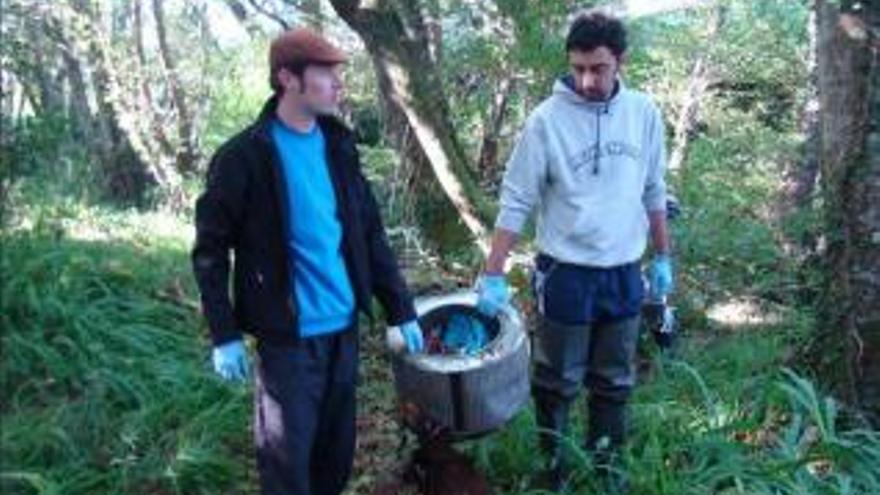 Dos participantes en la jornada de limpieza muestran el tambor de una lavadora.  // O Fervedoiro