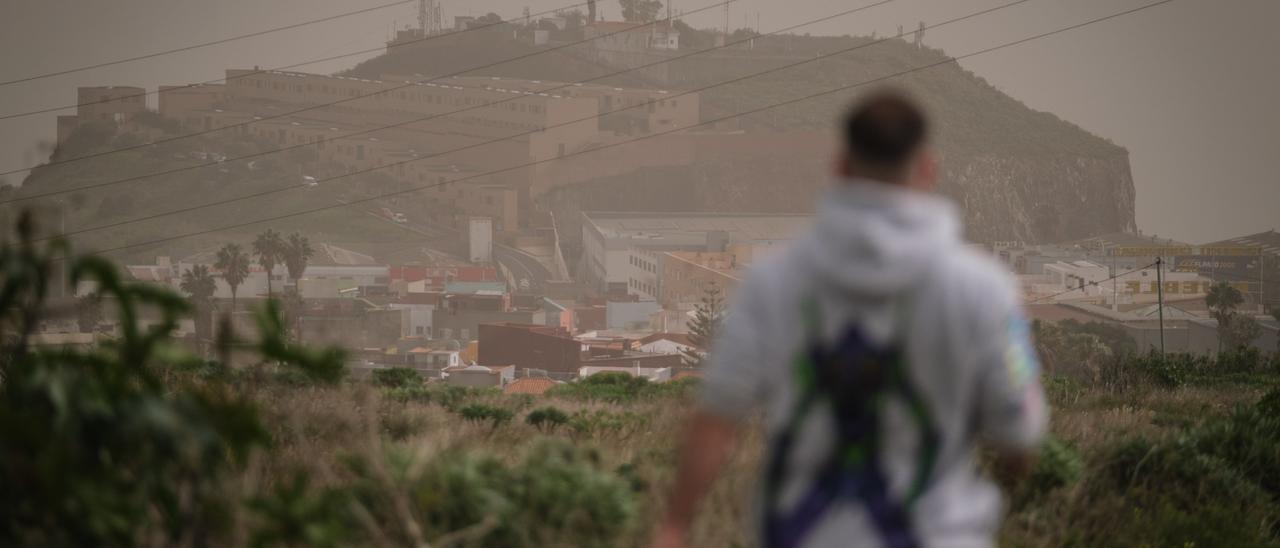 Un hombre camina con la baja visibilidad de la calima.