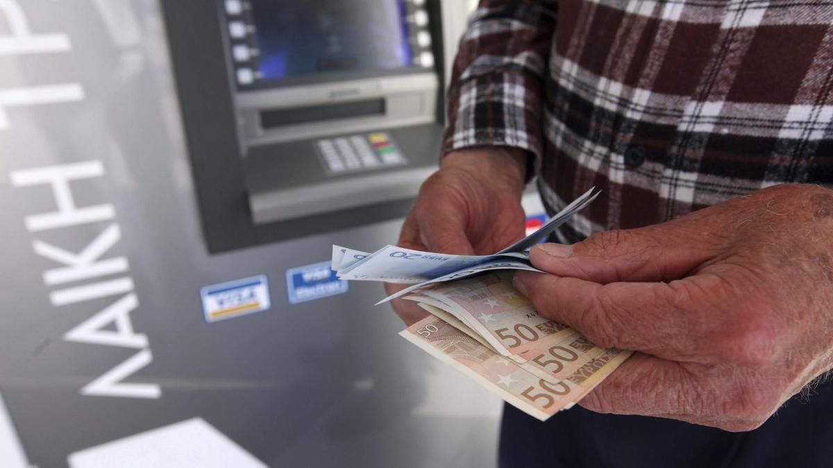 Un hombre saca dinero del cajero.