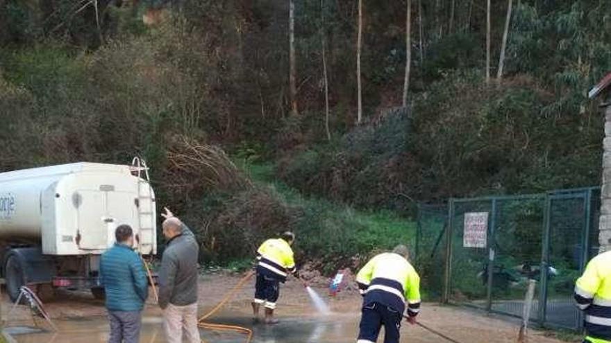 Trabajadores de Daorje baldeando la zona próxima al campo de fútbol, ayer.