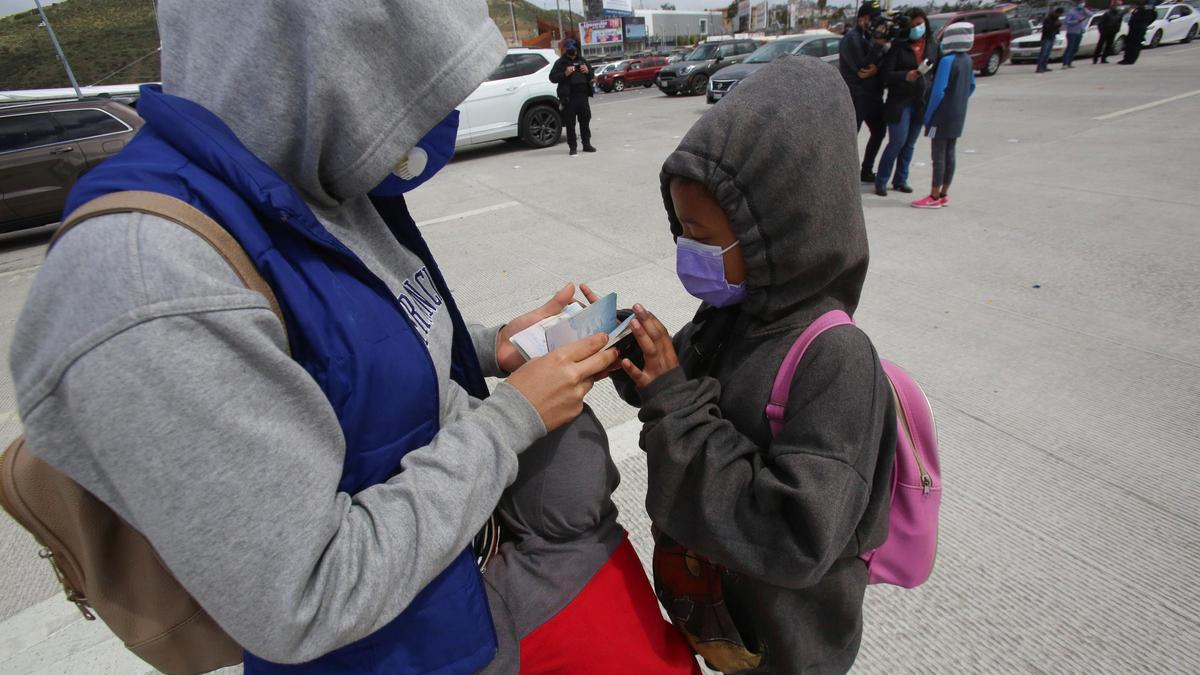 Migrantes en Tijuana comprueban sus pasaportes.