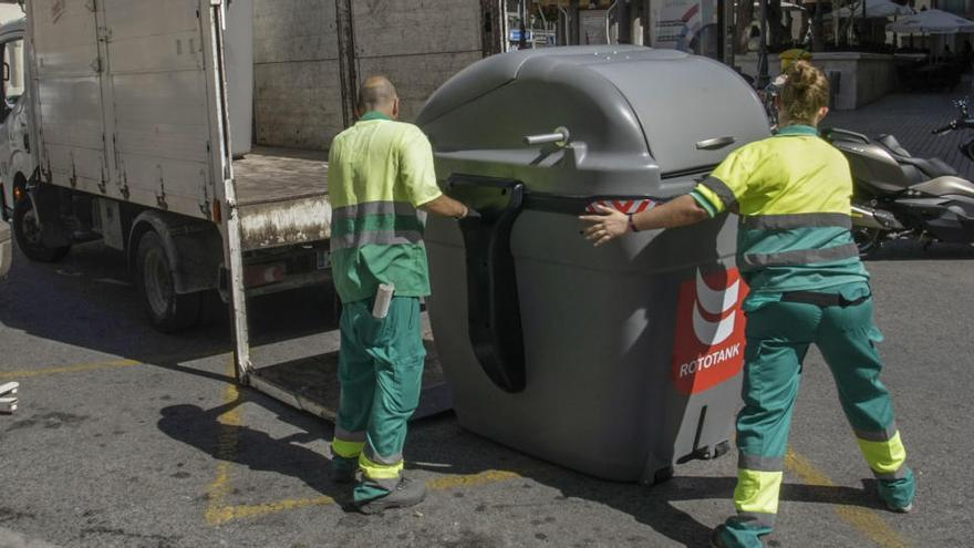 Dos trabajadores de la limpieza retiran un contenedor de pruebas en el centro de la ciudad