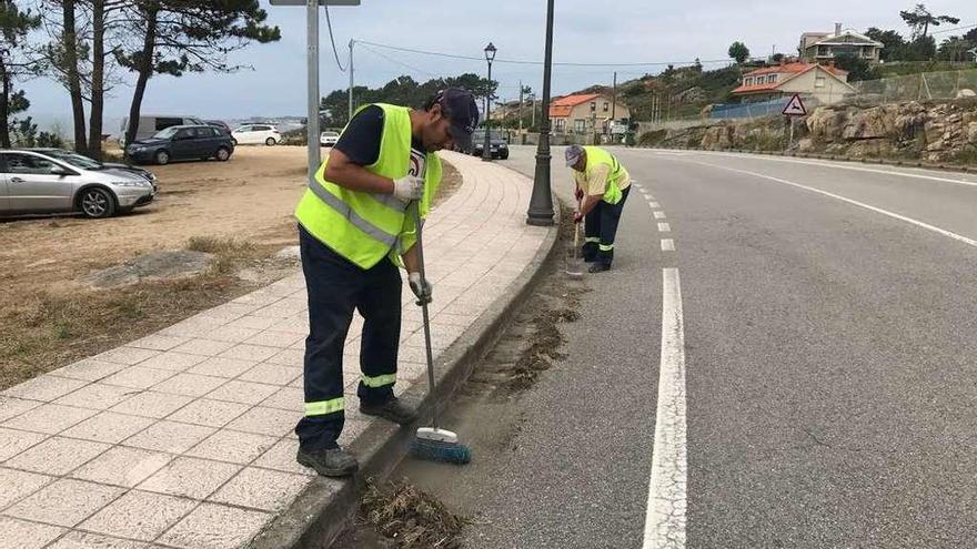 Operarios municipales en plena limpieza de la carretera entre A Lanzada y Pedras Negras. // Muñiz