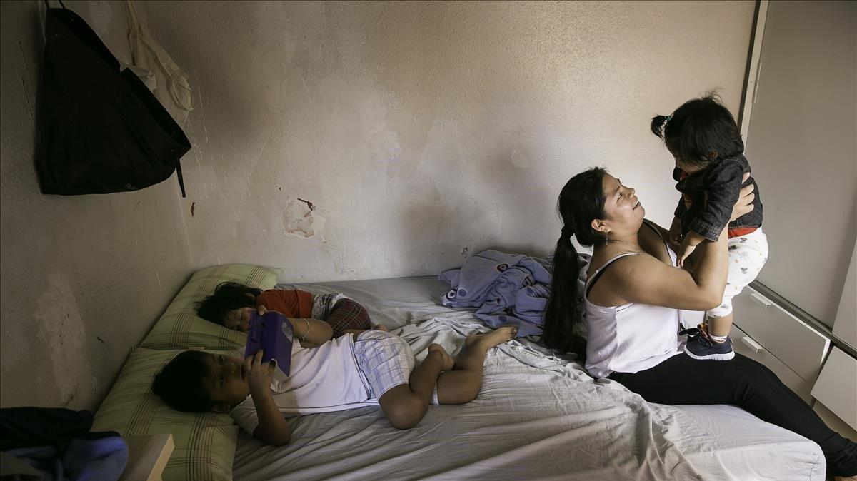 Marlene Marcos, junto a sus dos hijos Eydan (8 años) y Laia (3 años), sostiene la hija de una amiga para que la madre pueda ir a trabajar. 