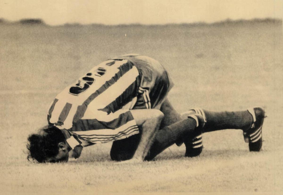 Quini besa el césped de El Molinón en el día de su despedida del fútbol.