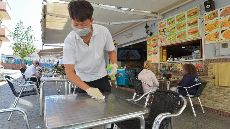 Un camarero desinfecta la mesa de una terraza en Arguineguín.