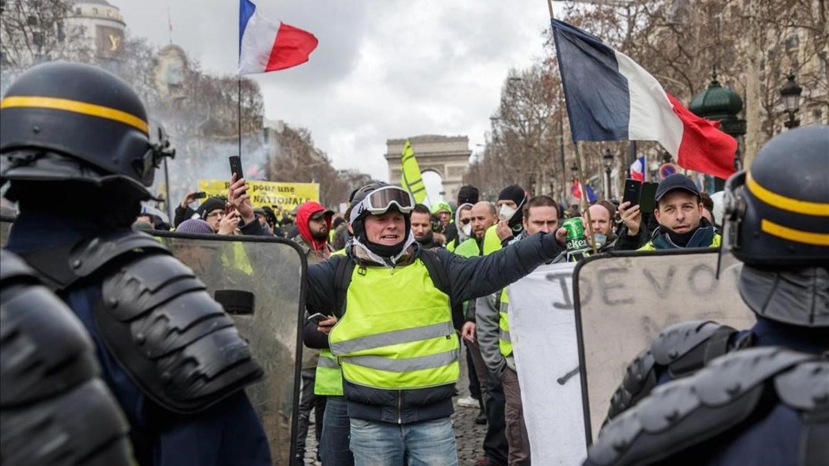 Manifestantes de los 'chalecos amarillos' protestan ante la policía en los Campos Elíseos, en París.