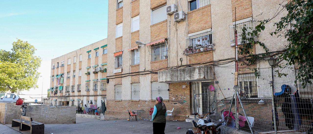 Una mujer pasa frente a un bloque de pisos en los que se alquila uno de los inmuebles más baratos de Alicante, en el barrio de Juan XXIII.