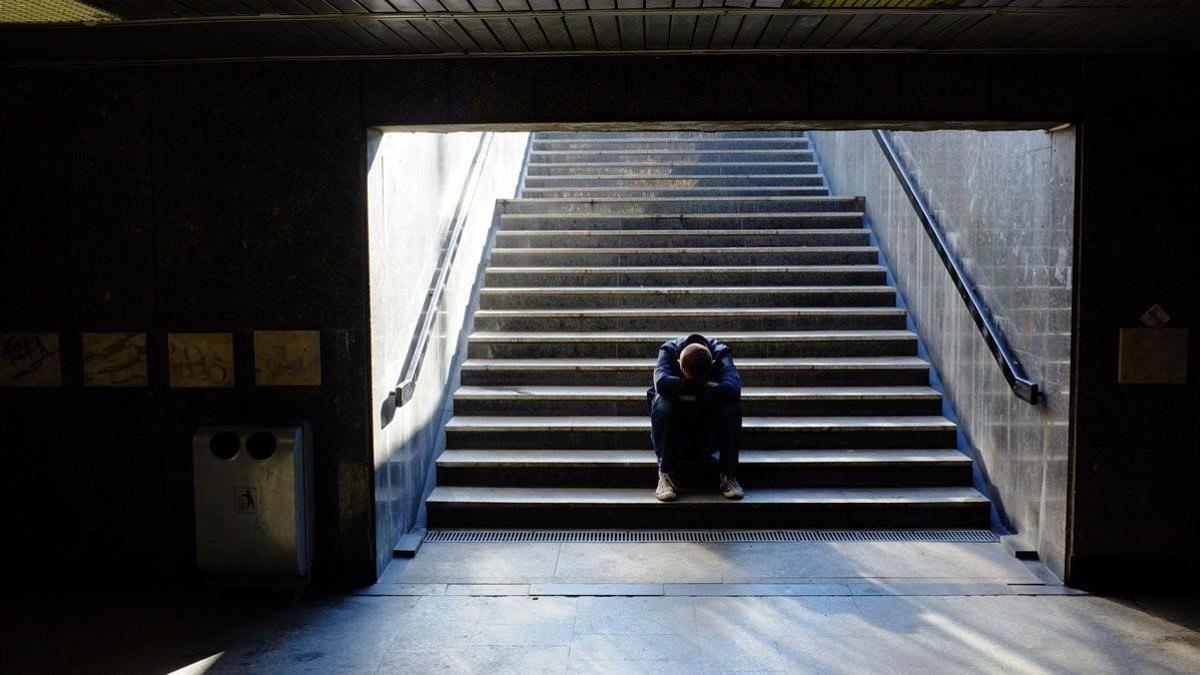 Un joven sentado en las escaleras de la boca del metro.