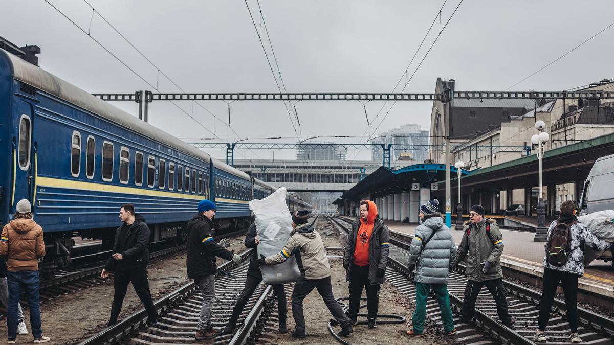 Varios voluntarios transportan ayuda humanitaria en la estación de tren de Kiev.