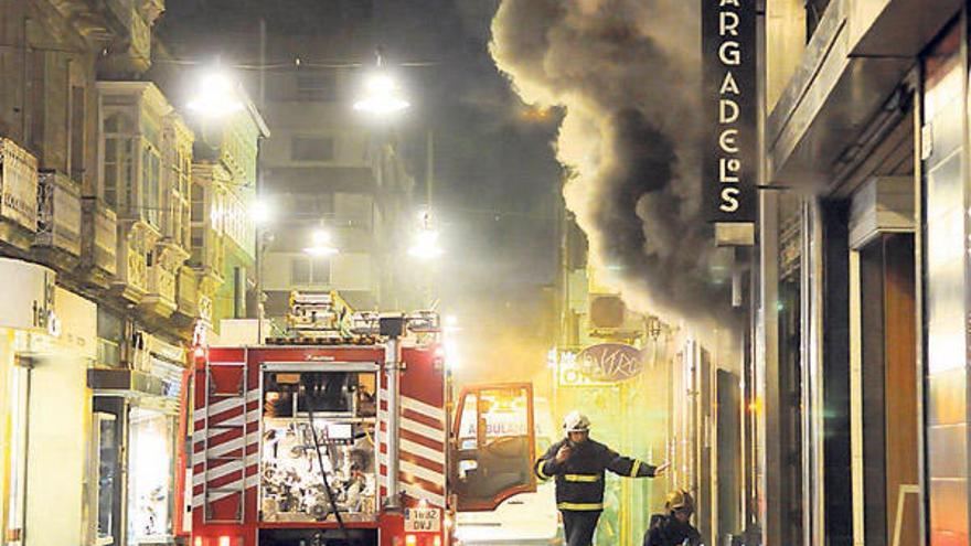 Los bomberos ante la densa humareda que durante horas salió del local de la droguería.  // G. Santos