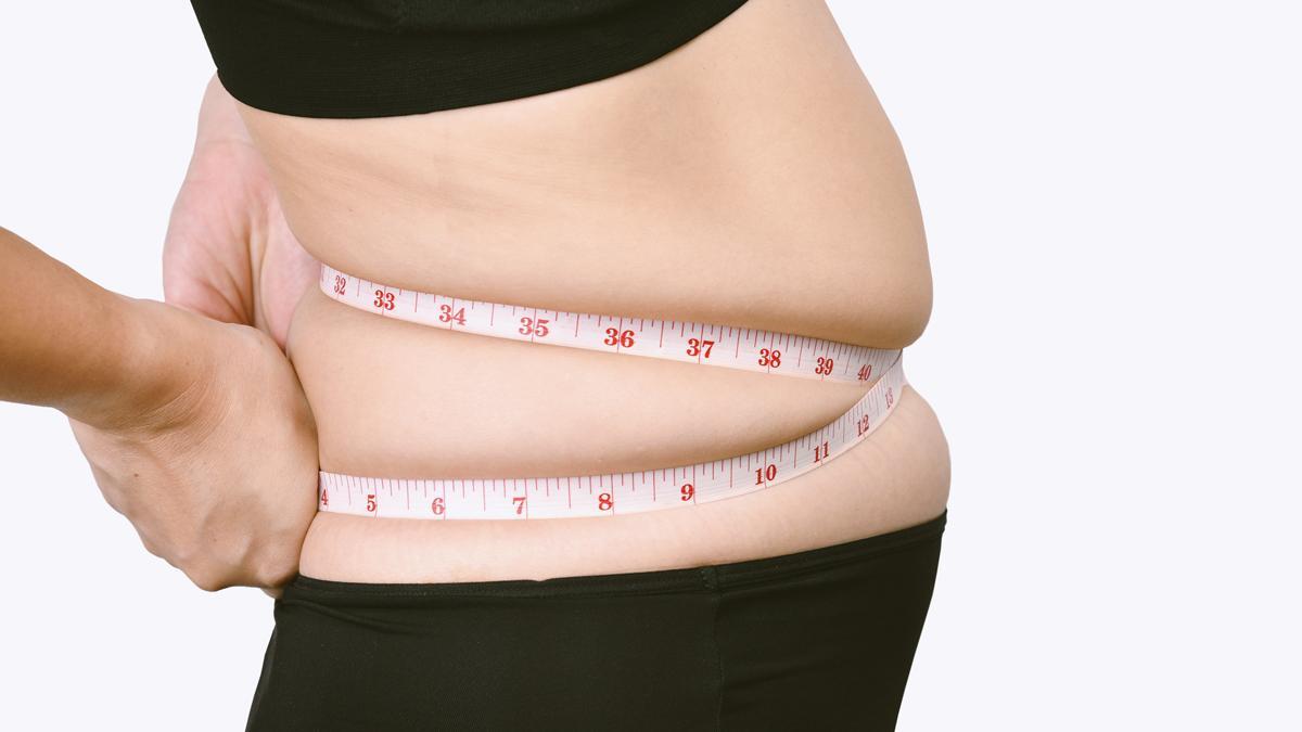 Una mujer mide el contorno de su cintura