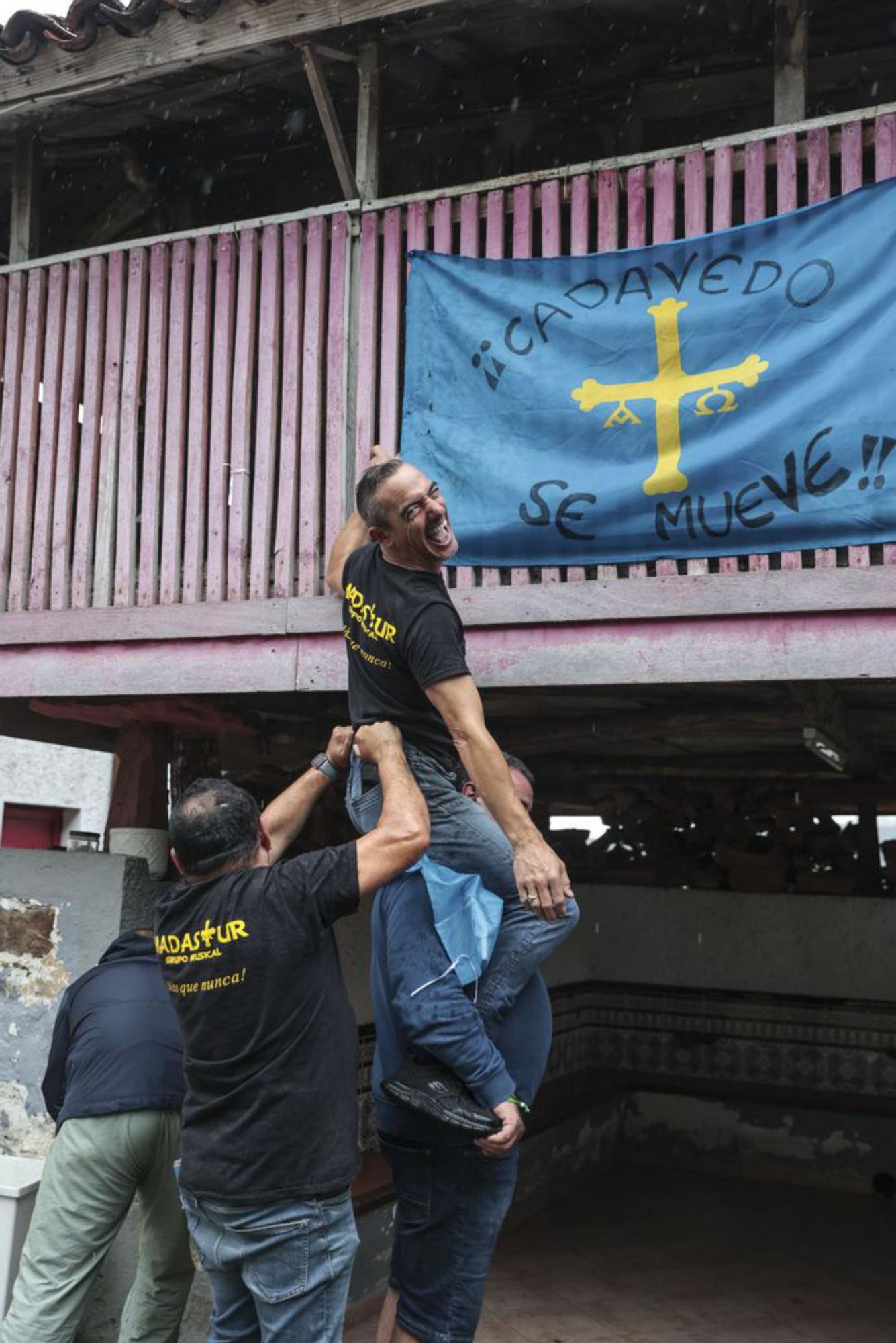 Juan Carlos Guerrero es ayudado a colocar una bandera en el hórreo del Casino. | Irma Collín
