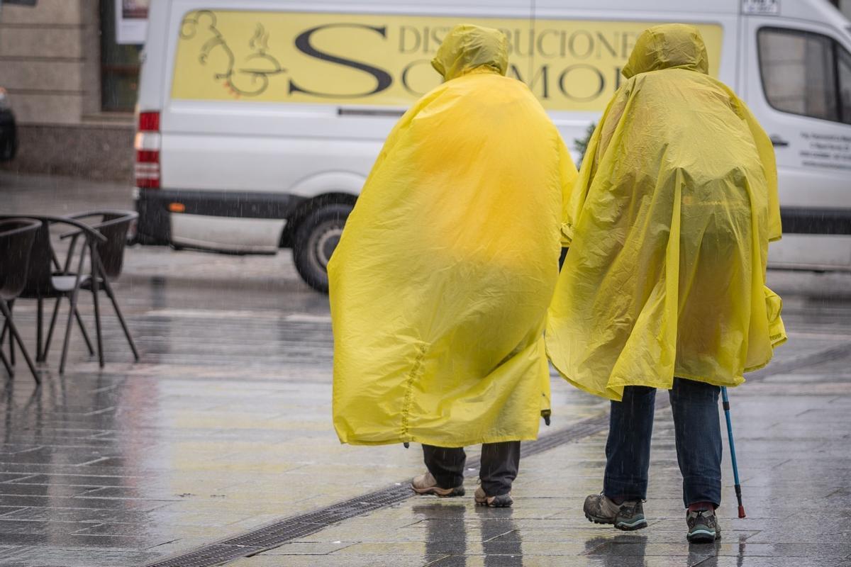 Turistas, en Mérida, se protegen de la lluvia con chubasqueros.