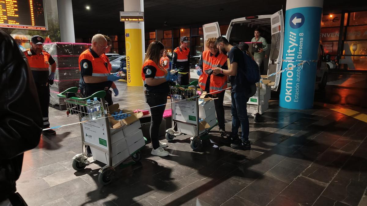 Varios voluntarios de Protección Civil reparten agua y víveres a pasajeros en la estación de autobuses de Delicias.