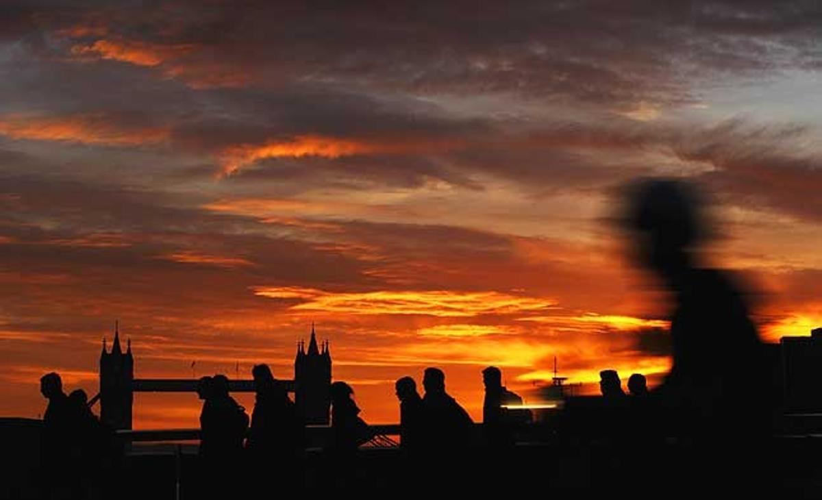 Unes persones es dirigeixen a la feina travessant el pont de Londres amb la clàssica imatge del pont de la Torre com a fons, a Londres (Regne Unit).