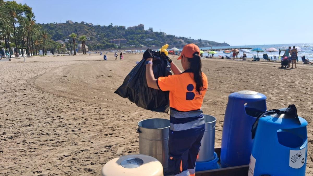 Una operaria del servicio de limpieza retira residuos en uno de los puntos de recogida instalados en las playas de Benicàssim, donde ya se han recogido más de 52 toneladas esta temporada.