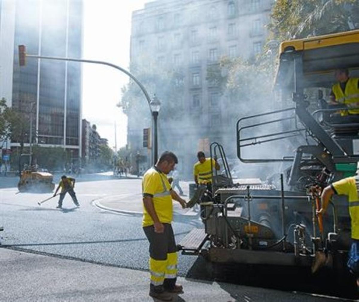 Uns obrers realitzen obres d’asfaltatge en un tram de l’avinguda Diagonal i, a la dreta, imatge del bolcat d’asfalt en un tram del carrer d’Aragó, ahir.