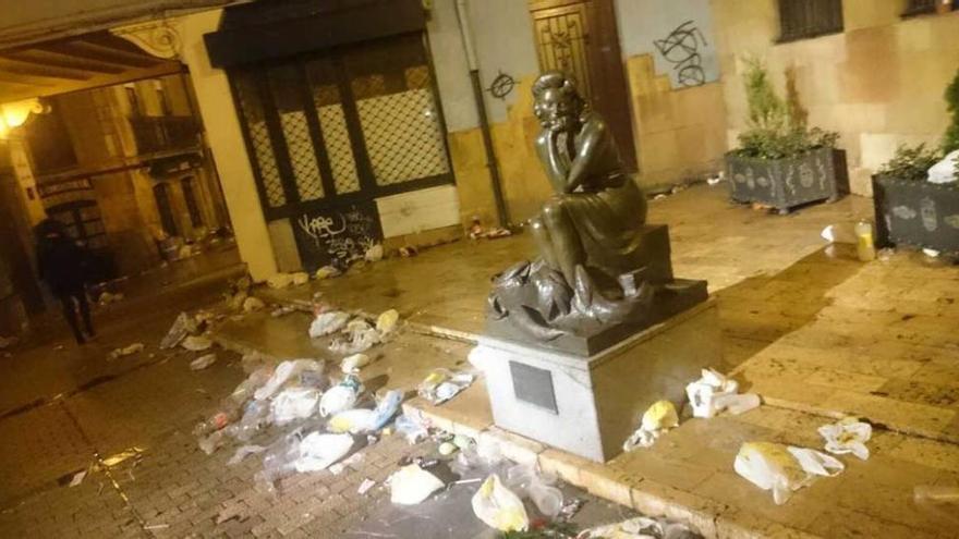 &quot;La pescadera&quot;, resaca entre basura. La plaza de Trascorrales fue uno de los lugares elegidos para beber en la calle. Cuando el &quot;botellón&quot; se disolvió, la escultura que preside una parte de la plaza, &quot;La Pescadera&quot;, quedó rodeada de bolsas de basura y restos de botellas.