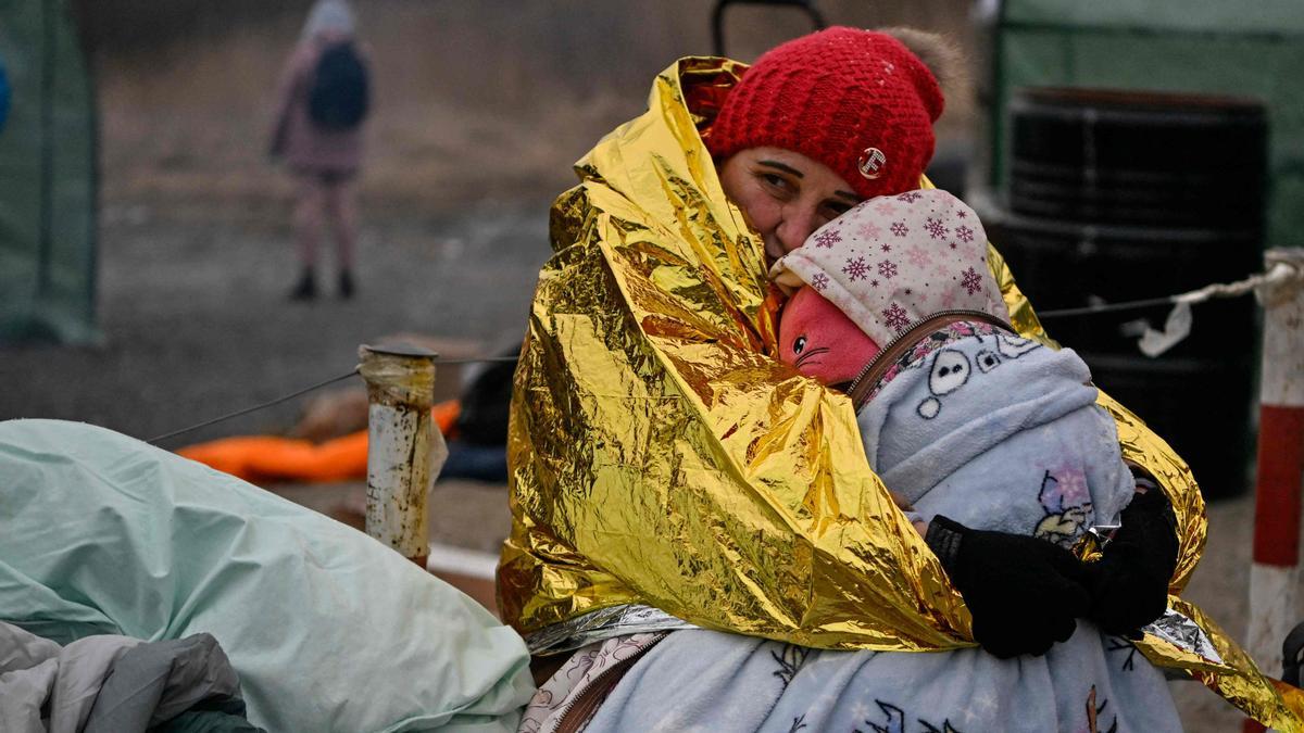 Una mujer abraza a su hija mientras ambas esperan ser trasladadas a una estación de tren tras cruzar el paso fronterizo de Medyka, en Polonia.