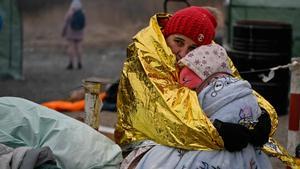 Una mujer abraza a su hija mientras ambas esperan ser trasladadas a una estación de tren tras cruzar el paso fronterizo de Medyka, en Polonia.