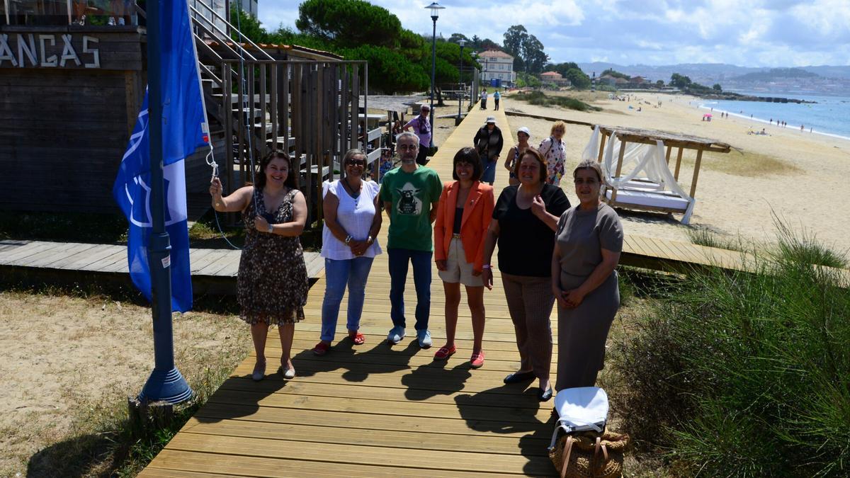 La alcaldesa y otros miembros del gobierno tripartito, izando la bandera azul en la playa de Rodeira.