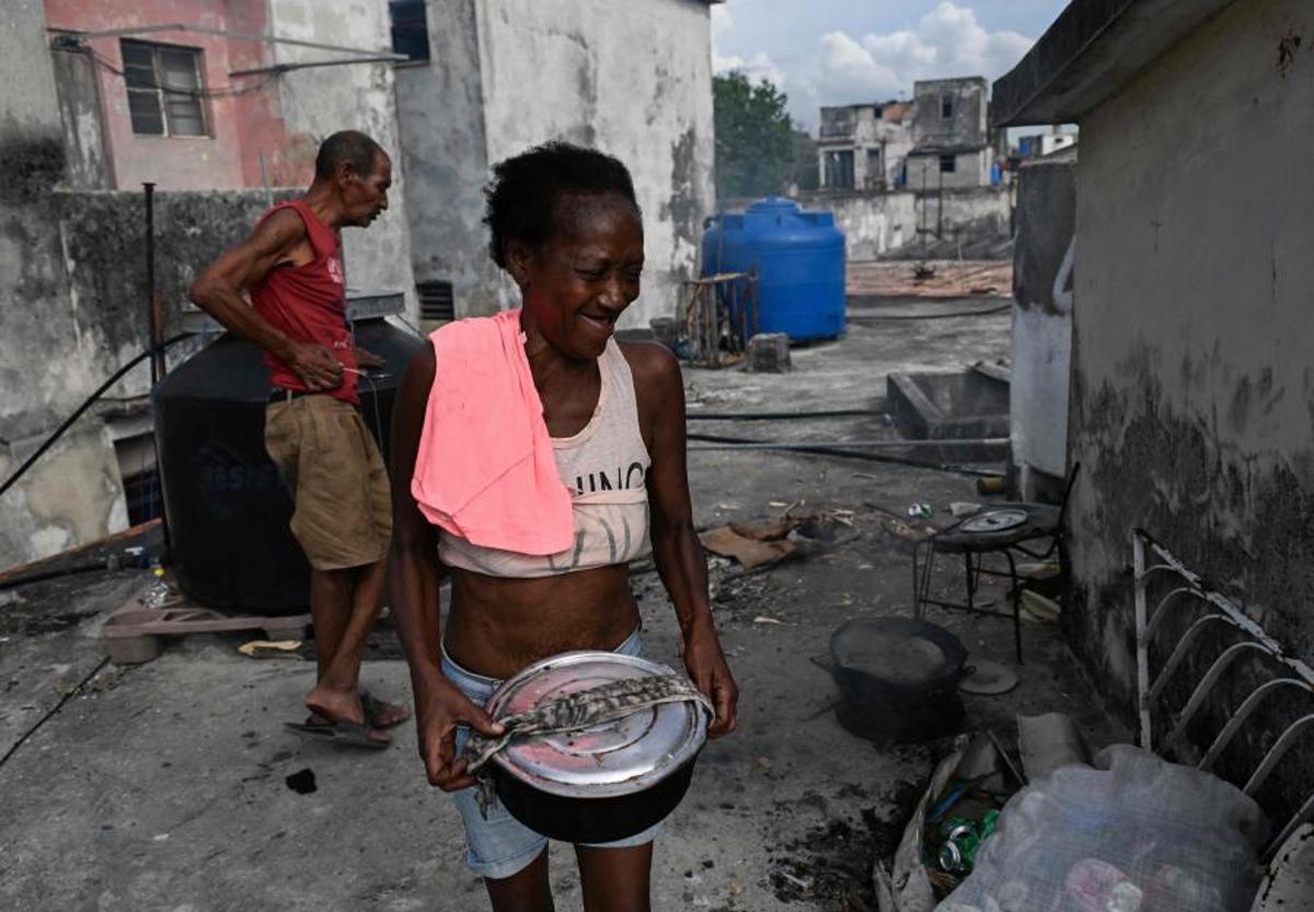 Una mujer sonríe mientras transporta una olla de comida durante un apagón en La Habana, Cuba, el 13 de mayo de 2026. El gobierno cubano atribuyó a Estados Unidos la situación “particularmente tensa” de su red eléctrica, marcada por apagones prolongados, mientras Washington ha ofrecido nuevamente 100 millones de dólares en ayuda a la isla.