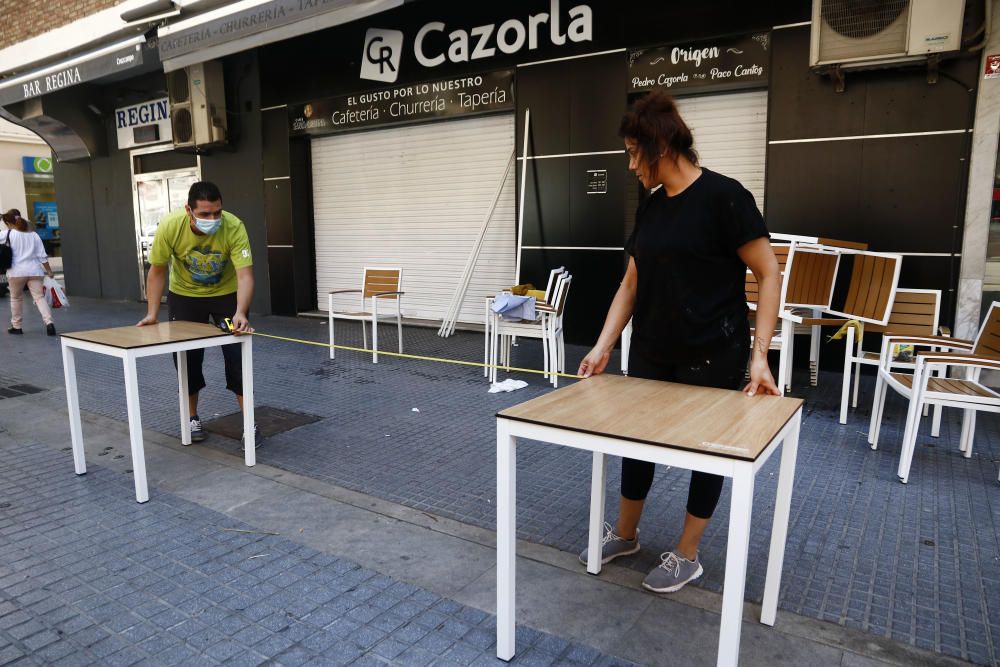 Imágenes de una lluviosa mañana de jueves en el centro de Málaga, donde al paisaje ya habitual de pocas personas y la mayoría de ellas con guantes y mascarillas se le han añadido los preparativos de bares, cafeterías y terrazas que se preparan para el inminente cambio de fase de la desescalada de la ciudad.