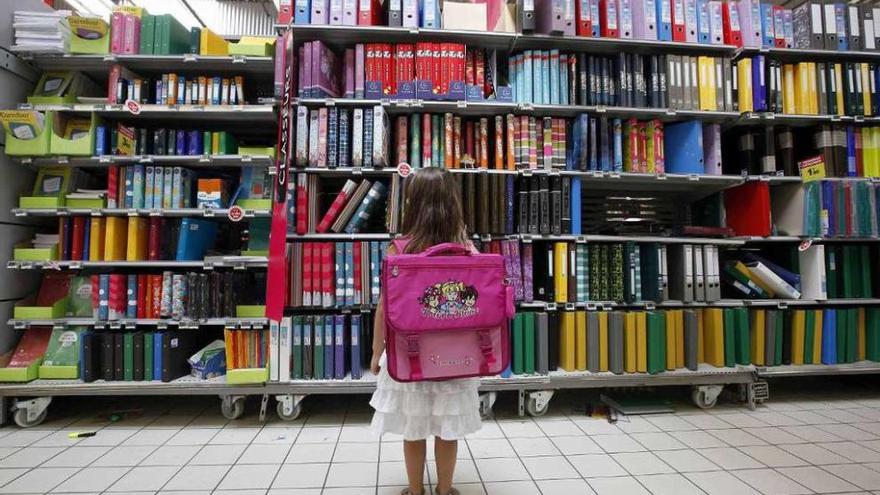 Una niña mira las entanterías de un hipermercado llenas de material escolar.