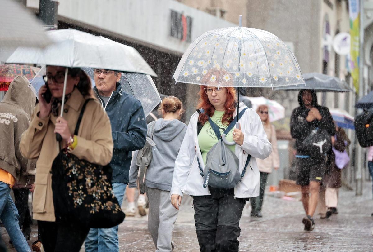 Los chicharreros se protegen de la lluvia, ayer, en el centro de Santa Cruz de Tenerife. | MARÍA PISACA