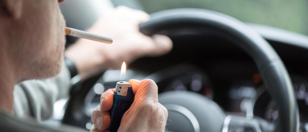 Un conductor encendiéndose un cigarrillo.