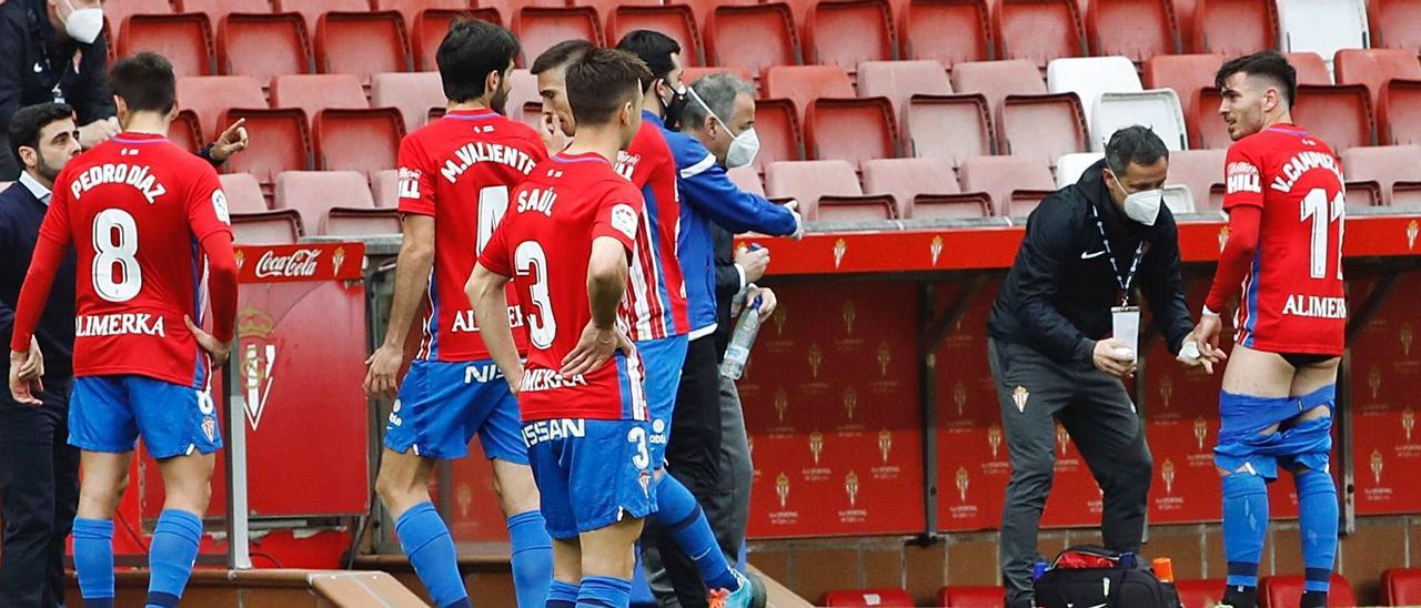 Campuzano, a la derecha, es atendido por Diego Lobelle, ante jugadores y auxiliares del Sporting. | Á. González
