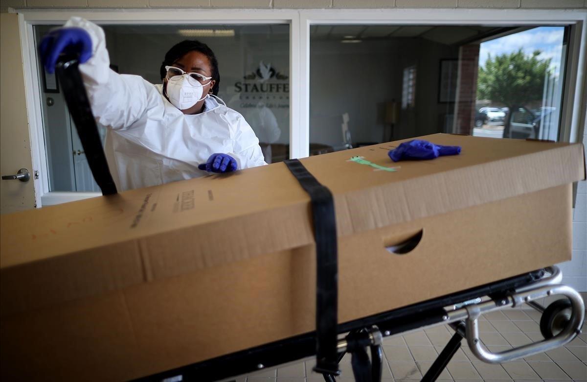 Una operaria del servicio de la funeraria prepara una caja con un cadáver para su posterior cremación.