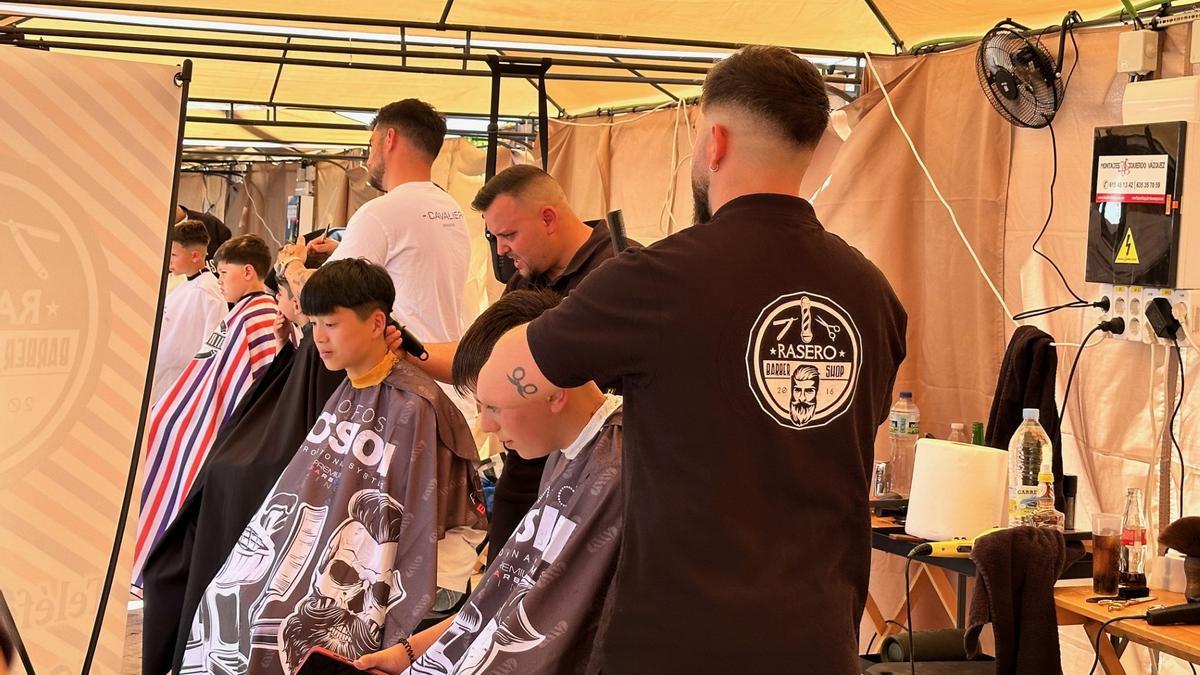 Barberos haciendo cortes solidarios en plaza de Extremadura.