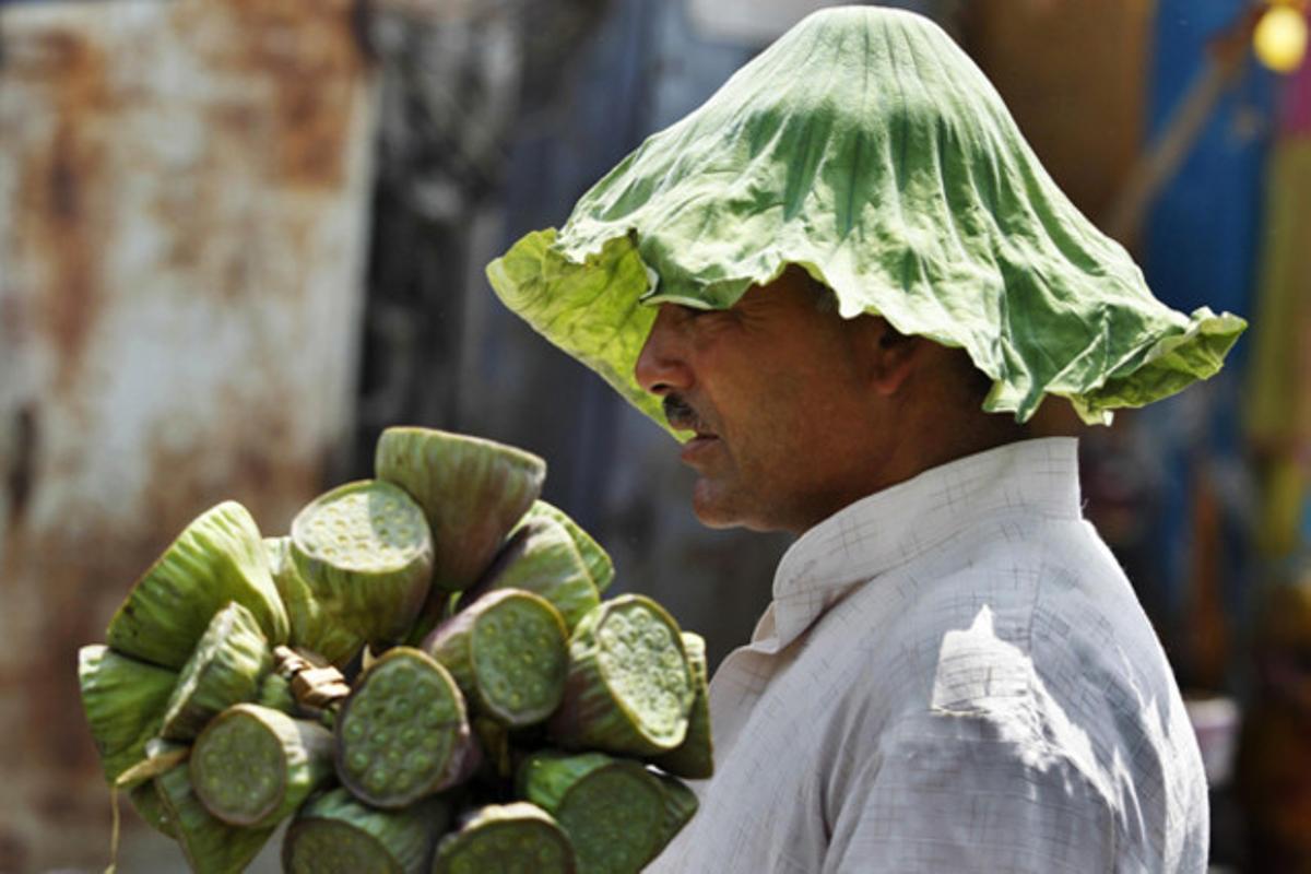 Un venedor indi es cobreix el cap amb un lotus en un mercat de la regió de Caixmir(Índia).