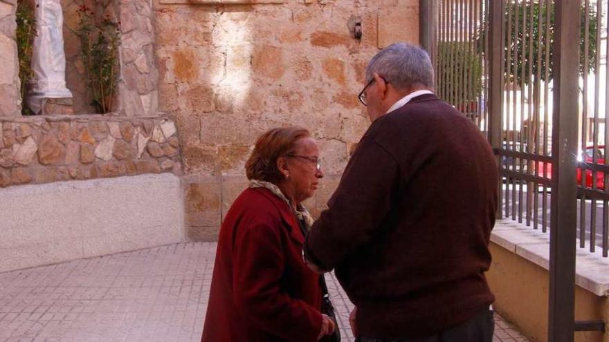 Dos personas observan la imagen de Lourdes, aún tapada, en la hornacina. .