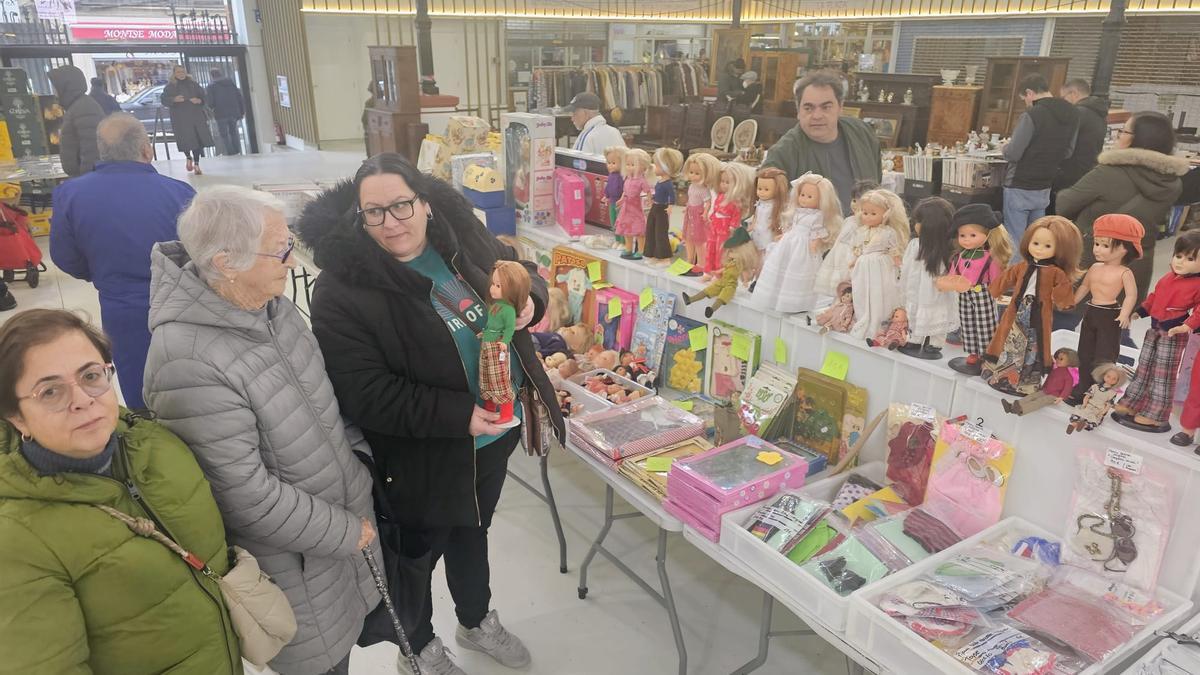 Marta Hermida enseña a Kati Soto y Teresa Villazon una muñeca Nancy expuesta en el mercadillo.