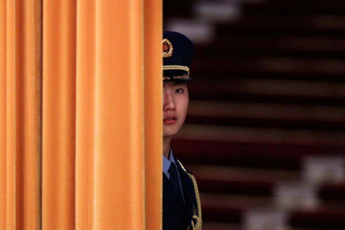 Un membre de la guàrdia d’honor espera darrere d’una cortina abans de desfilar en la cerimònia de benvinguda al president polonès Bronislaw Komorowski, a Pequín (Xina).