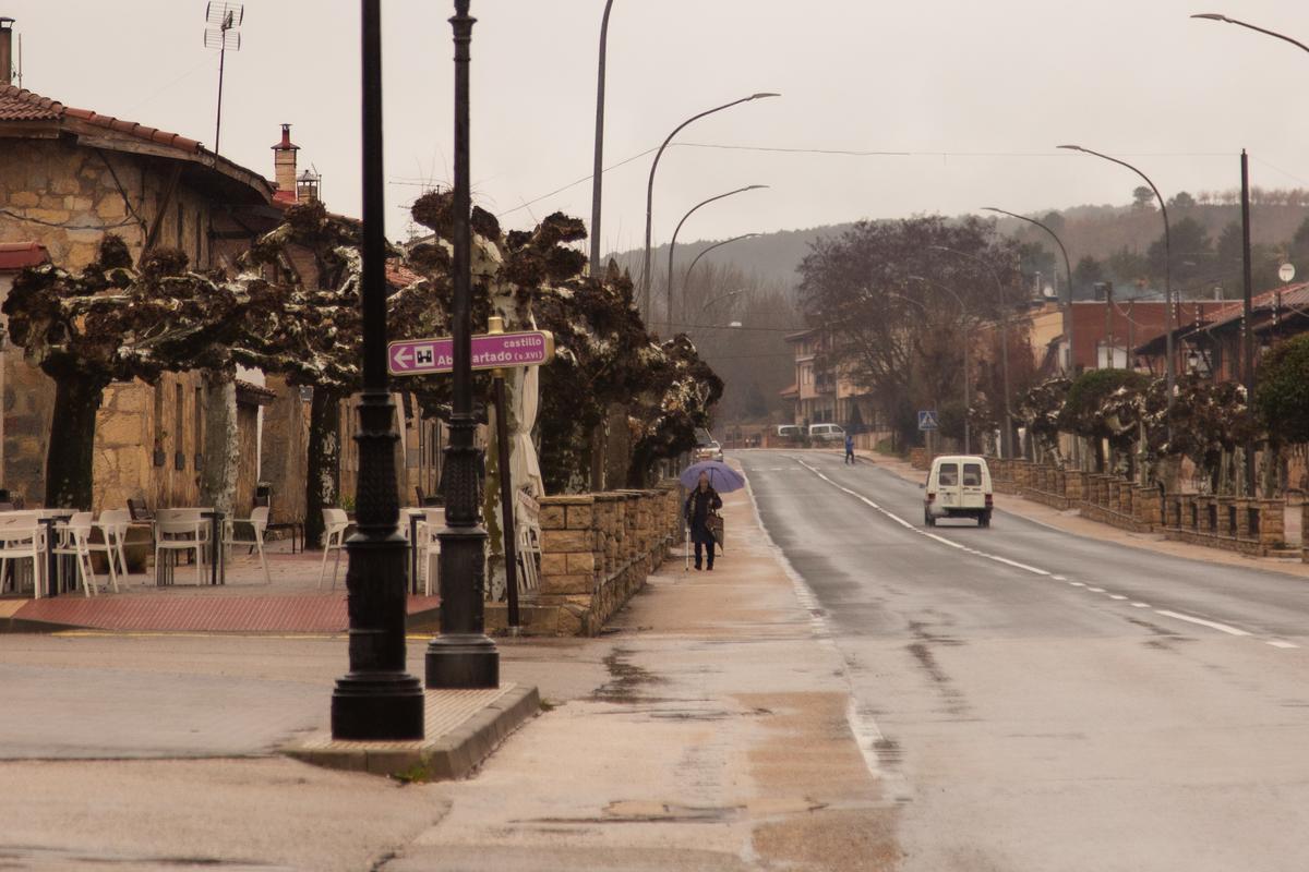 Una vecina se resguarda bajo el paraguas de la lluvia en una de las calles del pueblo.